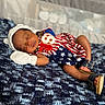 baby, sleeping, infant, blanket, knitted_blanket, hat, white_hat, sandals, footwear, clothing, red, white, blue, stars, stripes, cute, peaceful, indoor, portrait, child