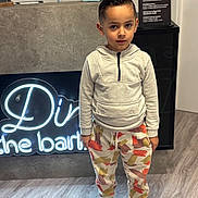 Titi a rejoint le concours — aidez-le/la à gagner de superbes lots ! child, boy, hoodie, colorful_pants, sneakers, barbershop, neon_sign, floor, standing, indoor, haircut, casual_clothing, modern, young, curious_expression, fashion, portrait, lighting, concrete_wall, shop_interior