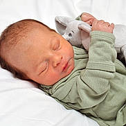 Giovanni is registered to the contest to win money with this photo: newborn, baby, sleeping, plush_toy, elephant, green_onesie, infant, peaceful, soft_texture, blanket, cute, child, portrait, resting, closeup, indoors, skin, hand, face, cozy