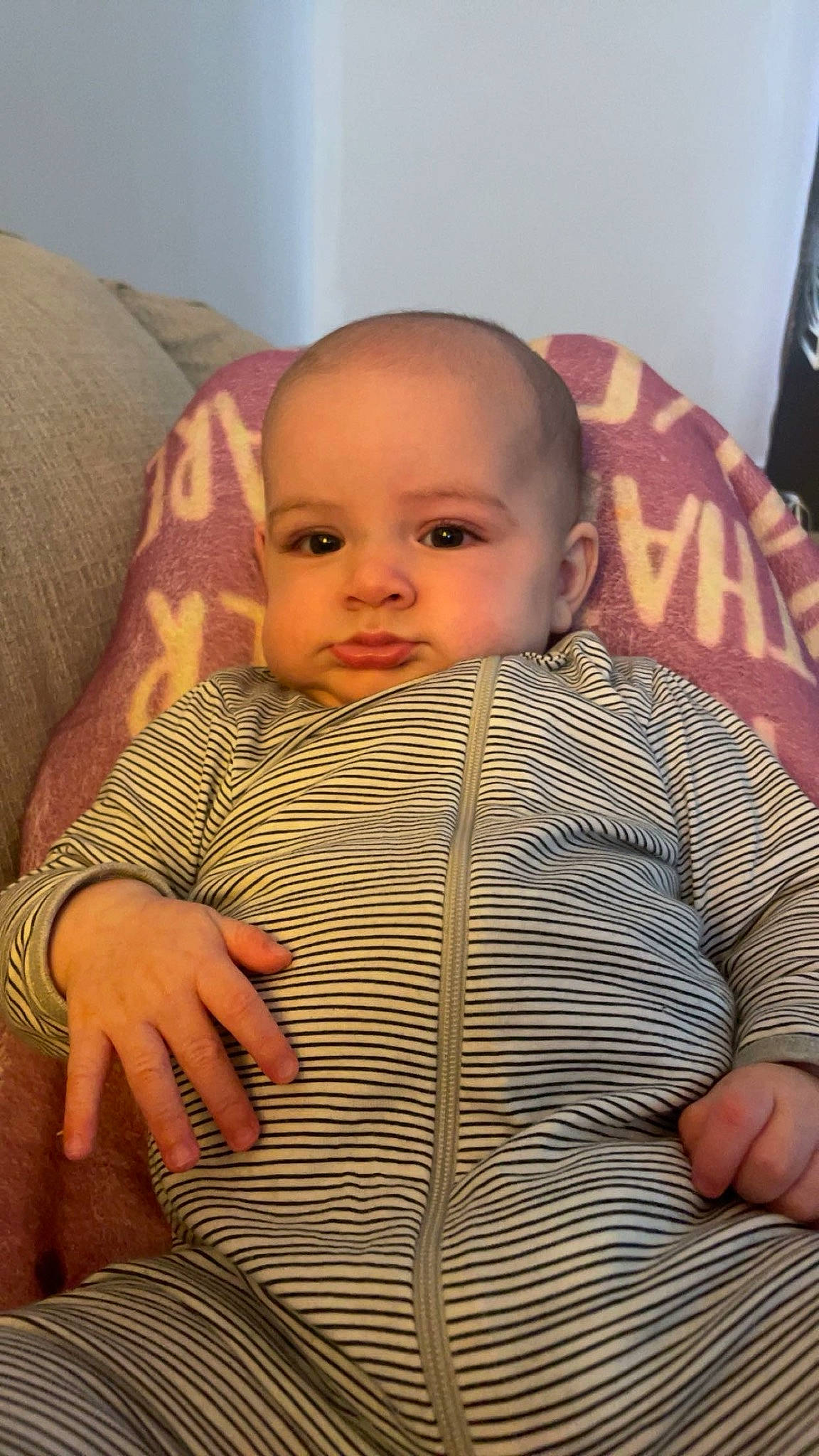 Eli is registered to the contest to win money with this photo: baby, baby_toddler_clothing, cheek, child, chin, comfort, eye, eyebrow, finger, iris, linens, lip, mouth, nose, pattern, person, sitting, skin, sleeve, thumb