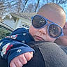 Junior is registered to the contest to win money with this photo: baby, child, sunglasses, blue, hand, face, outdoor, sky, trees, house, clothing, person, holding, shoulder, reflection, sunlight, casual, portrait, expression, daylight