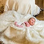 baby, infant, white_blanket, fur_rug, floor, wood_floor, bedroom, bed, blanket, wrapped, lying_down, curious, indoor, soft_texture, cozy, child, person, newborn, cute, resting
