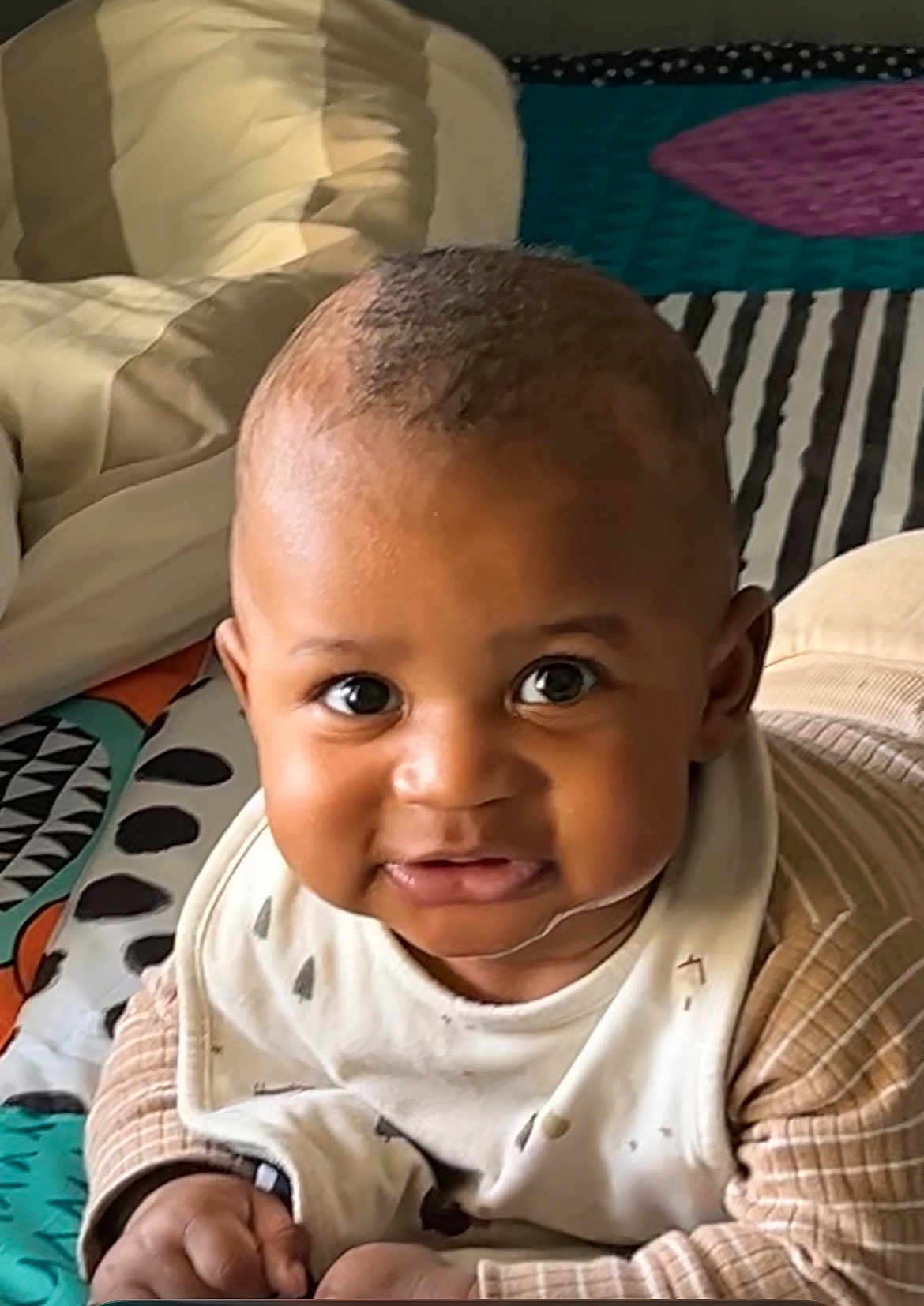 Issadya a rejoint le concours — aidez-le/la à gagner de superbes lots ! baby, infant, child, face, smile, eyes, clothing, bib, patterned_blanket, striped, cute, indoors, portrait, young, skin, hands, lying_down, head, expression, warm_light