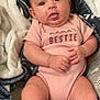 Zariah is registered to the contest to win money with this photo: baby, infant, onesie, pink_clothing, blanket, cute, tongue_out, smiling, chubby_arms, chubby_legs, face, skin, indoors, soft_texture, cozy, young_child, person, happy, relaxed, lying_down