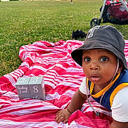 baby, child, hat, bucket_hat, blanket, striped_blanket, grass, outdoor, nature, mountain, lake, sunset, stroller, blocks, numbers, picnic, curious, crawling, person, park