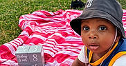 Taytum is registered to the contest to win money with this photo: baby, blanket, blocks, bucket_hat, child, crawling, curious, grass, hat, lake, mountain, nature, numbers, outdoor, park, person, picnic, striped_blanket, stroller, sunset