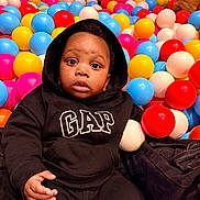Taytum joined the competition — help win amazing prizes! baby, ball_pit, black_clothing, bright_colors, casual_wear, child, colorful, cute, expression, fun, gap, hoodie, indoor, infant, looking, plastic_balls, play_area, portrait, seated, young_child