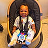 Taytum is registered to the contest to win money with this photo: baby, baby_feet, baby_rocker, baby_toy, black_cushion, child, cute, floor, floor_tiles, happy, harness, indoor, infant, pajamas, patterned_clothing, playful, seat, smiling, toy, wooden_frame
