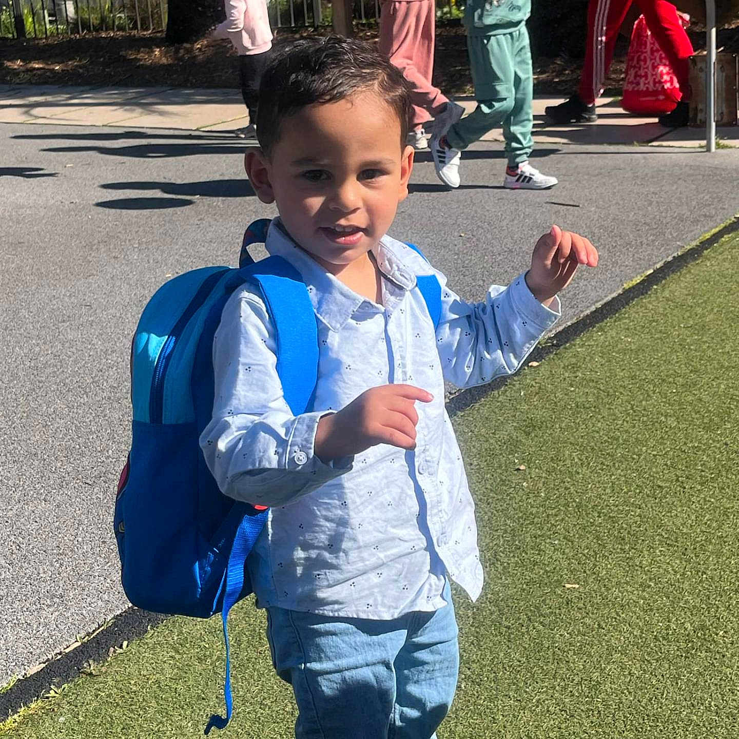 Arslan a rejoint le concours — aidez-le/la à gagner de superbes lots ! backpack, blue, boy, casual_clothing, child, daytime, grass, jeans, kids, outdoor, people, person, playground, shadows, shirt, sidewalk, smiling, sunlight, urban, walking