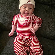 Scarlett joined the competition — help win amazing prizes! baby, smiling, infant, striped_clothing, hat, red_and_white, sitting, couch, happy, cute, child, face, apparel, cozy, indoor, person, portrait, young, fun, relaxed