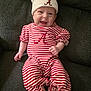 baby, smiling, infant, striped_clothing, hat, red_and_white, sitting, couch, happy, cute, child, face, apparel, cozy, indoor, person, portrait, young, fun, relaxed