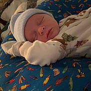 Riley is registered to the contest to win money with this photo: newborn, baby, sleeping, hat, clothing, cushion, pattern, fish, colorful, cozy, indoor, resting, infant, soft, blanket, cute, portrait, peaceful, child, young