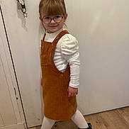 Lya participe au concours pour gagner de l'argent avec cette photo : black_shoes, brown_dress, casual, child, cute, door, door_handle, fashion, girl, glasses, hair_bangs, indoor, keys, long_sleeve_shirt, playful, smiling, standing, white_tights, wooden_floor, young_child