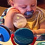 Aurora joined the competition — help win amazing prizes! baby, child, pacifier, milk_bottle, sleeping, toys, high_chair, indoor, cute, infant, hand, face, clothing, yellow_shirt, closeup, soft_light, peaceful, young, person, portrait