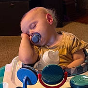Aurora is registered to the contest to win money with this photo: toddler, baby, sleeping, pacifier, bottle, baby_walker, toy, carpet, indoor, child, infant, clothing, relaxation, nap, person, furniture, home, cute, peaceful, resting