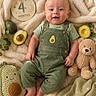 Apollo joined the competition — help win amazing prizes! baby, infant, smiling, green_overalls, avocado, teddy_bear, knitted_pillow, blanket, leafy_greens, soft_texture, cute, child, lying_down, happy, four_months, portrait, cozy, plush_toy, natural_light, indoor