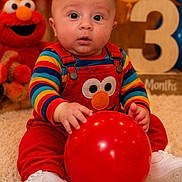 Apollo is registered to the contest to win money with this photo: baby, infant, balloon, red_balloon, colorful_clothing, elmo, stuffed_toy, carpet, celebration, birthday, number_three, wooden_number, smiling_toy, white_shoes, striped_shirt, indoor, child, cute, portrait, happy