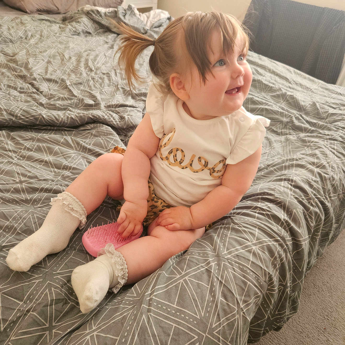 Sophie is registered to the contest to win money with this photo: baby, bed, bedspread, carpet, child, clothing, curious, cute, furniture, hair, hairbrush, indoor, light, person, pillow, playful, room, smiling, socks, toddler