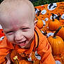 baby, child, pumpkin, orange_clothing, blanket, halloween, autumn, outdoor, smiling, cute, festive, fall, playful, person, head, face, hand, small_pumpkins, seasonal, holiday