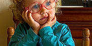 Agathe a rejoint le concours — aidez-le/la à gagner de superbes lots ! blue_eyes, child, clothing, curly_hair, cute, face, glasses, hands, home, indoor, long_sleeve, pacifier, portrait, sitting, table, tablecloth, thoughtful, toddler, wooden_chair, wooden_furniture