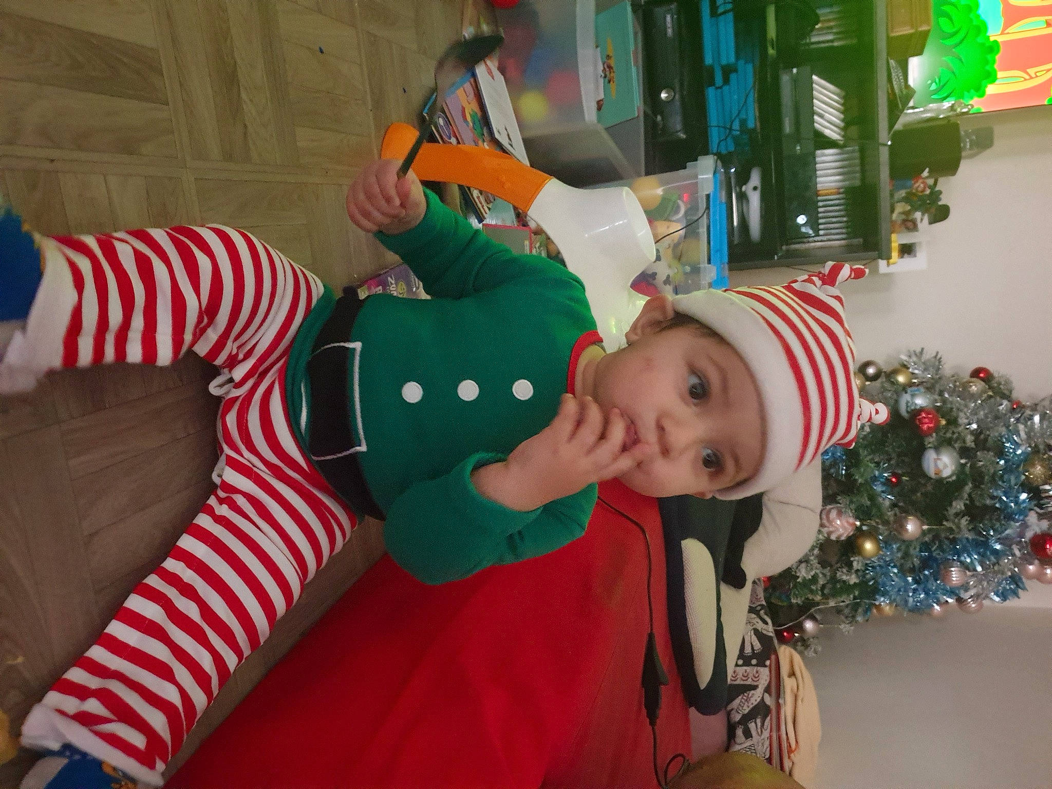 Maxence participe au concours pour gagner de l'argent avec cette photo : baby_toddler_clothing, carmine, child, christmas, christmas_decoration, christmas_eve, christmas_ornament, christmas_tree, event, fictional_character, fun, green, happy, headwear, holiday, lap, person, red, room, sleeve
