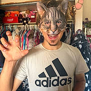 Hunter joined the competition — help win amazing prizes! cat, cat_mask, person, human, portrait, smiling, open_mouth, playful, costume, cosplay, animal_mask, claw_pose, hand, glass, shirt, adidas, closet, clothing, wardrobe, indoor