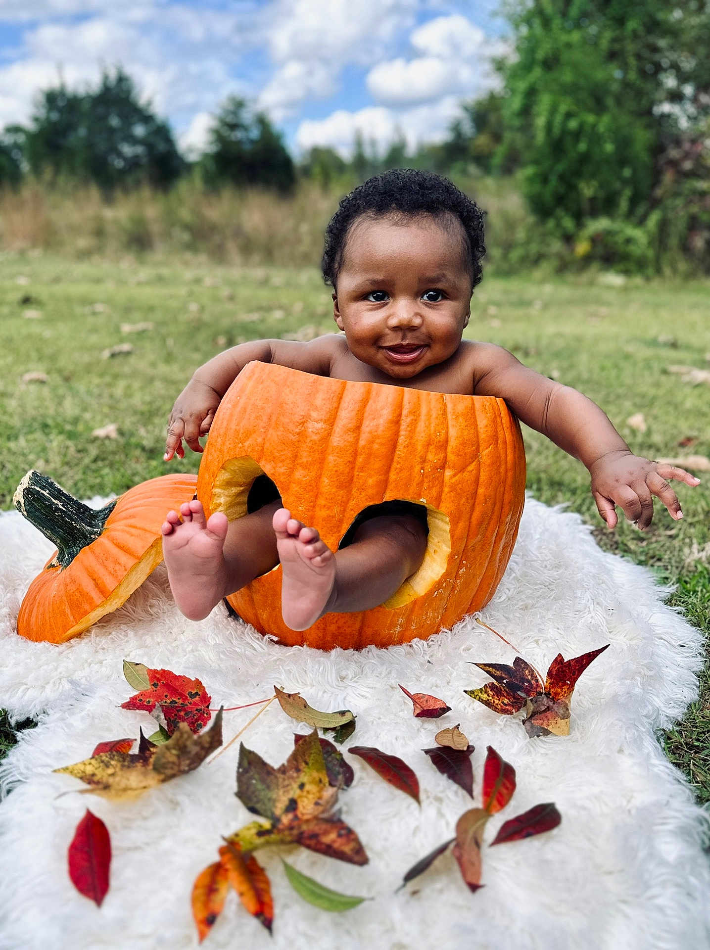 Jahaad is registered to the contest to win money with this photo: baby, pumpkin, autumn_leaves, outdoor, grass, blanket, smiling, child, fall, nature, cute, happy, seasonal, playful, portrait, greenery, skin, feet, hands, sky