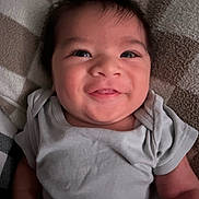 Westin joined the competition — help win amazing prizes! baby, smiling, face, infant, child, clothing, onesie, cheek, eyes, hair, skin, lying_down, soft_surface, pattern, blanket, happy, cute, portrait, indoor, young