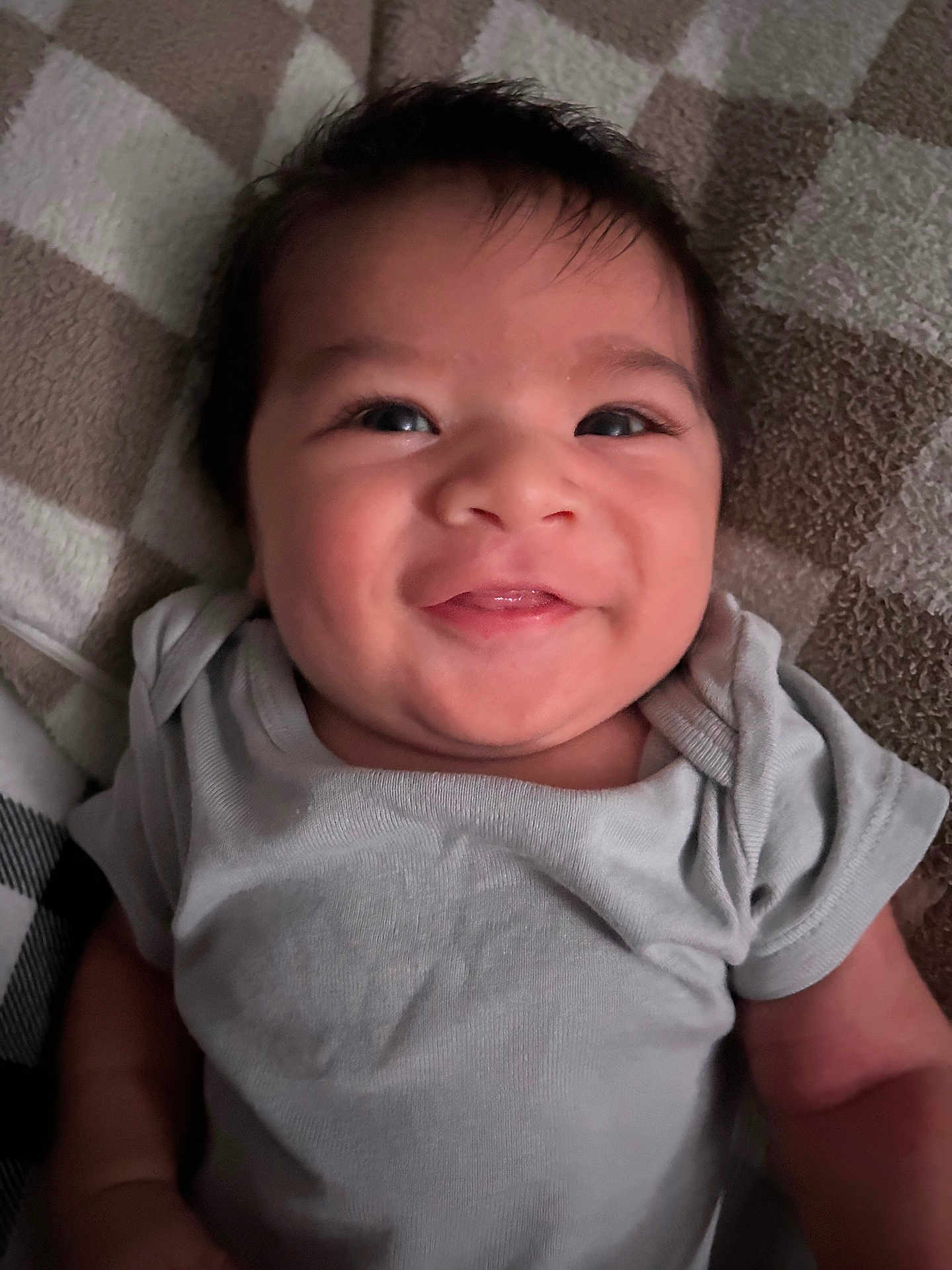 Westin joined the competition — help win amazing prizes! baby, smiling, face, infant, child, clothing, onesie, cheek, eyes, hair, skin, lying_down, soft_surface, pattern, blanket, happy, cute, portrait, indoor, young