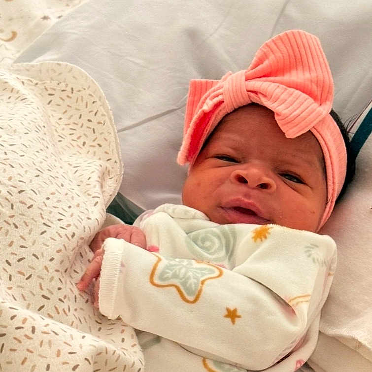 Dreame is registered to the contest to win money with this photo: baby, bed, blanket, child, cozy, cute, expression, face, hands, headband, indoors, infant, lying_down, newborn, patterned_blanket, pink_bow, portrait, sleep, sleepwear, soft_lighting