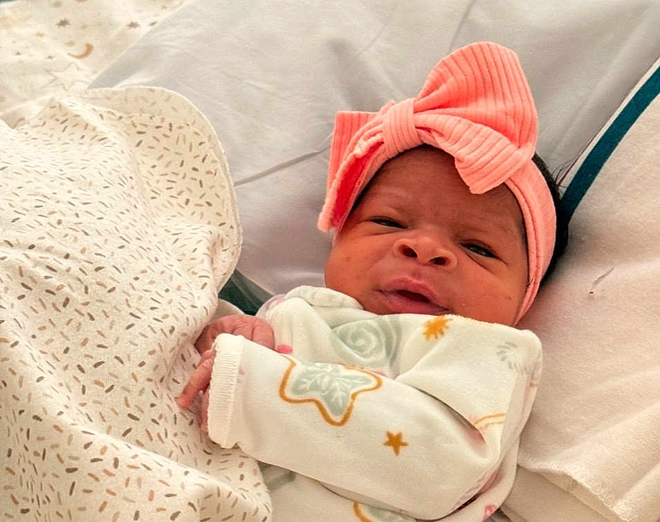 Dreame is registered to the contest to win money with this photo: baby, infant, headband, pink_bow, blanket, bed, sleepwear, patterned_blanket, cute, portrait, child, newborn, face, hands, lying_down, soft_lighting, indoors, cozy, expression, sleep