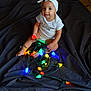 Braylee joined the competition — help win amazing prizes! baby, child, headband, onesie, colorful_lights, christmas_lights, indoor, dark_background, playing, smiling, sitting, floor, fabric, glowing, multicolor, cute, infant, toddler, holiday, decor