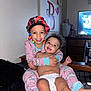 child, baby, siblings, pajamas, smile, hug, bed, blanket, diaper, indoor, television, dresser, happy, person, face, headwear, jewelry, room, furniture, family