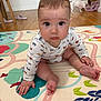 baby, child, infant, play_mat, floor, wooden_floor, dog, pet, indoor, cute, curious, pajamas, long_sleeve, colorful, patterned, hand, foot, face, expression, room
