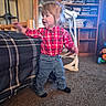 child, toddler, standing, plaid_shirt, jeans, socks, indoors, living_room, bookshelf, books, couch, carpet, walker, toy, furniture, portrait, profile, blonde_hair, motion, home
