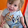 toddler, child, smiling, laughing, portrait, indoor, seated, blond_hair, blue_eyes, cartoon_clothing, pajamas, blanket, orange_background, playpen, baby, happy, closeup, person, casual, colorful