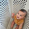 baby, child, smiling, laundry_basket, sitting, bib, socks, happy, cute, infant, playful, indoor, white, plastic, holes, closeup, portrait, cheerful, looking_up, young