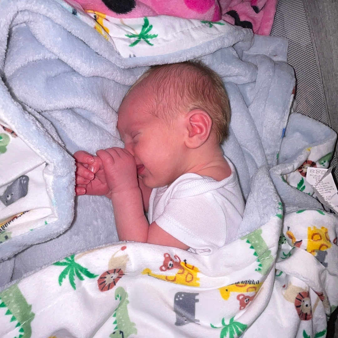 Toby is registered to the contest to win money with this photo: animal_print, baby, bed, blanket, child, comfort, cozy, cute, indoors, infant, newborn, peaceful, portrait, resting, sleeping, soft, thumb_sucking, toddler, white_clothing, wrapped