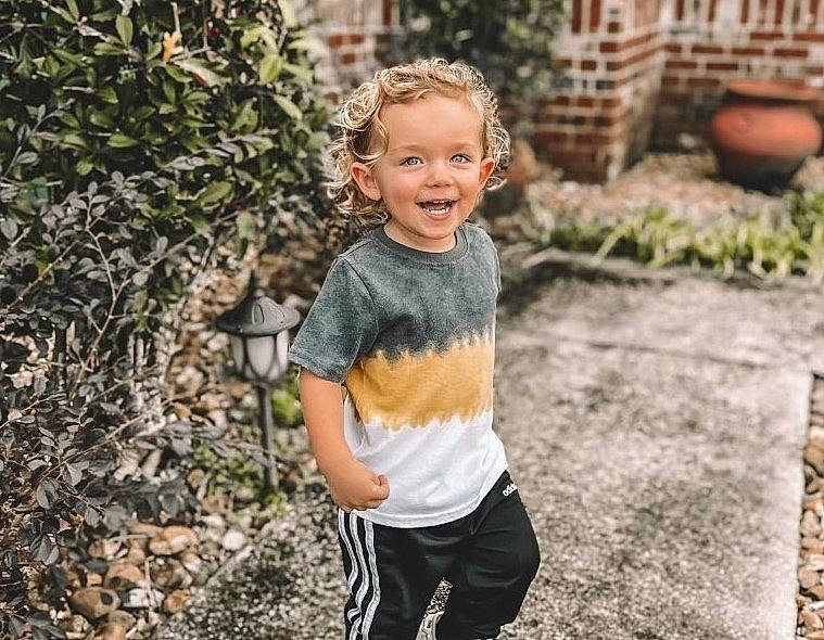 Bodhi is registered to the contest to win money with this photo: child, face, flash_photography, fun, grass, happy, head, human_body, joy, leisure, people_in_nature, person, plant, shorts, sitting, sleeve, smile, soil, sportswear, t_shirt