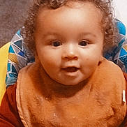 Nigel is registered to the contest to win money with this photo: baby, bib, cheeks, closeup, clothing, curly_hair, cute, eyes, feeding, hands, happy, highchair, indoor, infant, playful, portrait, seat, smiling, toddler, toy