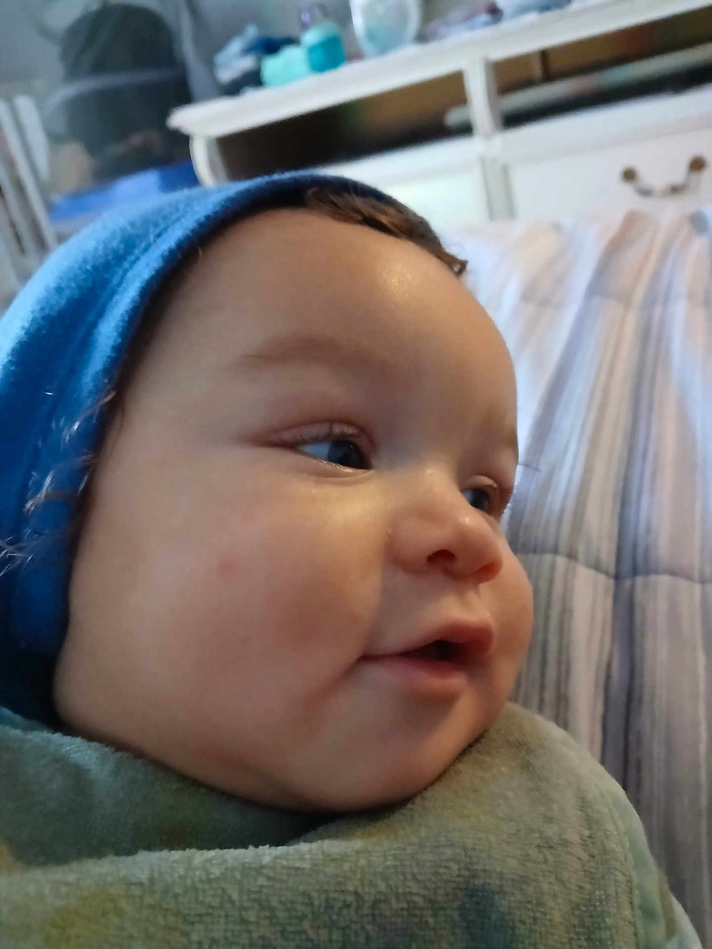 Nigel joined the competition — help win amazing prizes! baby, child, face, profile, blue_hat, blanket, indoor, bed, furniture, curious, skin, cheeks, headwear, infant, portrait, closeup, young_child, soft_light, sleeping_area, cozy