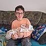 Mathieu a rejoint le concours — aidez-le/la à gagner de superbes lots ! child, baby, glasses, sofa, couch, blanket, pillow, newborn, smile, smiling, holding, sitting, indoor, portrait, jeans, sweatshirt, patterned_fabric, toy, home, family
