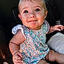 baby, child, car_seat, blue_eyes, smiling, floral_dress, cute, infant, skin, hand, face, sitting, portrait, young_child, indoors, seatbelt, clothing, person, happy, expression