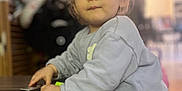 Julia participe au concours pour gagner de l'argent avec cette photo : toddler, child, indoor, table, pigtails, curious, young_child, clothing, face, person, hands, wooden_table, soft_lighting, room, background_blur, expression, standing, casual, home, playful