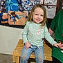 Freyja is registered to the contest to win money with this photo: background, bench, casual_clothing, child, christmas_tree, decorations, festive, girl, happy, holding_hands, holiday, indoor, jeans, long_hair, person, presents, smiling, sneakers, winter, wood