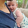 baby, smiling, face, arm, person, clothing, blue_shirt, skin, closeup, happy, infant, outdoor, nature, blurred_background, cuddle, holding, child, portrait, casual, daylight
