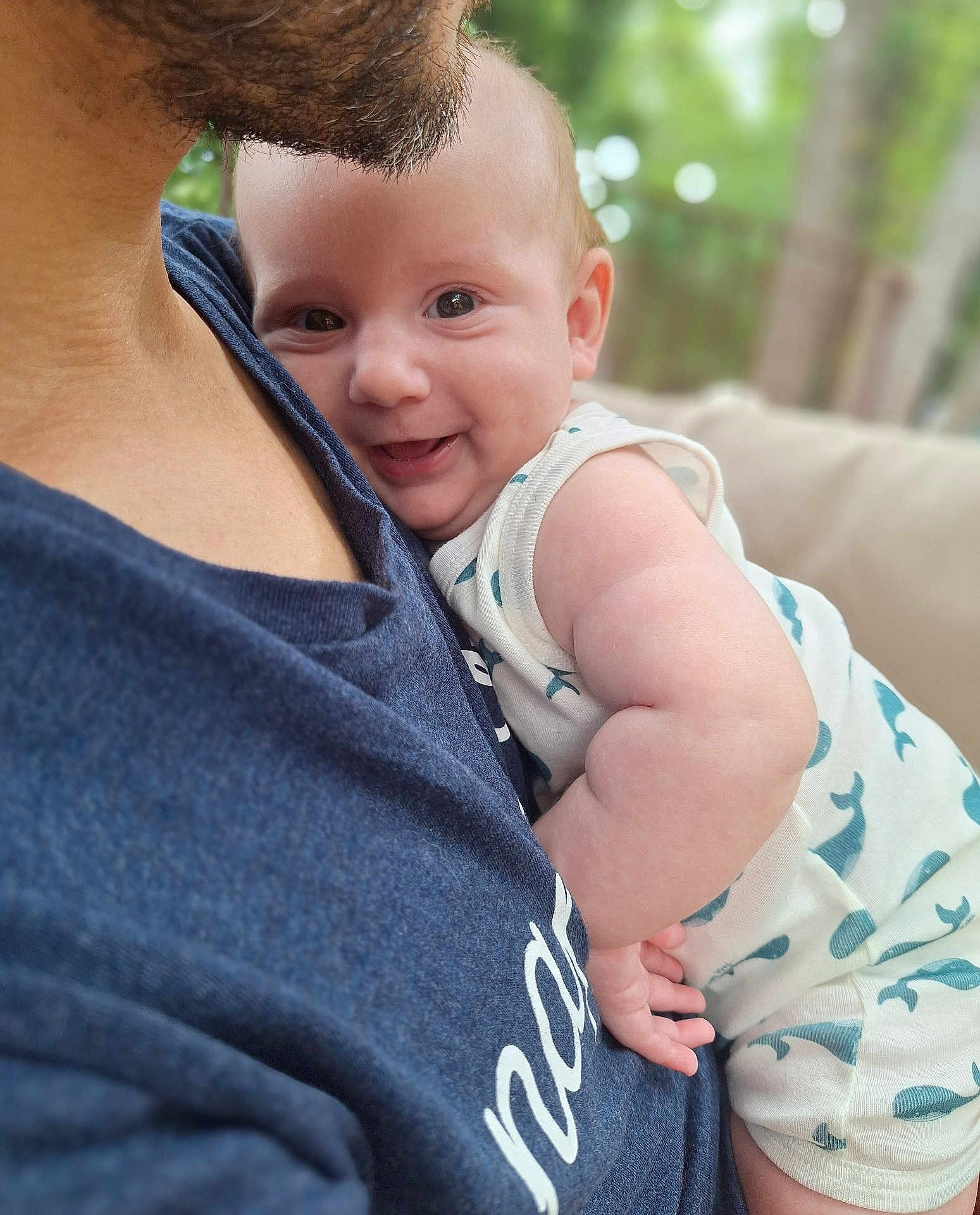 Sacha a rejoint le concours — aidez-le/la à gagner de superbes lots ! baby, smiling, face, arm, person, clothing, blue_shirt, skin, closeup, happy, infant, outdoor, nature, blurred_background, cuddle, holding, child, portrait, casual, daylight