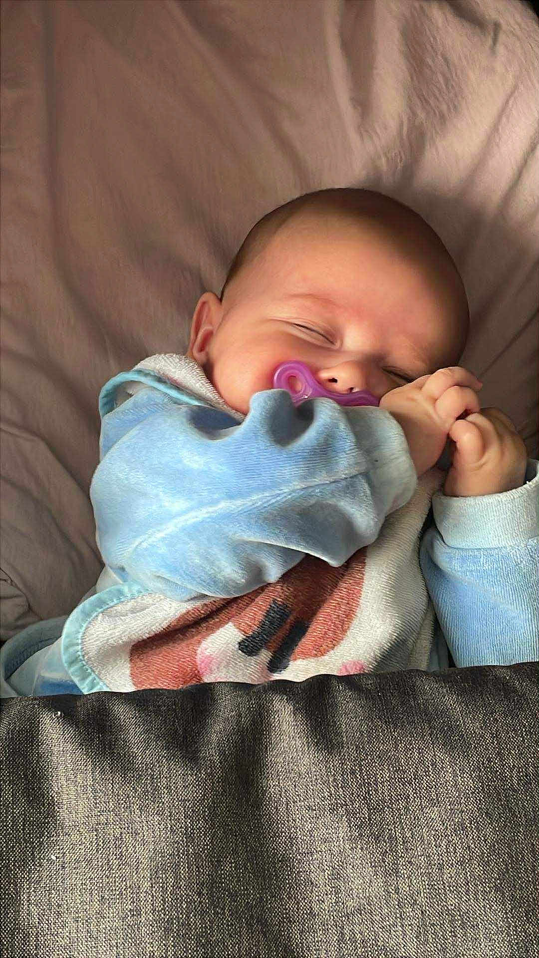 Nélya participe au concours pour gagner de l'argent avec cette photo : baby, sleeping, pacifier, blanket, bed, blue_clothing, infant, peaceful, cute, child, resting, soft, indoors, cozy, hands, face, head, young, toddler, comfort