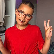 Mélyana participe au concours pour gagner de l'argent avec cette photo : child, glasses, red_shirt, peace_sign, indoor, smiling, short_hair, purple_lights, casual_clothing, person, young, happy, posing, bedroom, furniture, shelf, clothing, home, portrait, cheerful