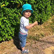 Lorenzo a rejoint le concours — aidez-le/la à gagner de superbes lots ! toddler, child, blue_hat, bucket_hat, white_tshirt, denim_shorts, sandals, outdoor, greenery, hedge, sunlight, pathway, summer, nature, curious, standing, side_view, grass, daytime, person